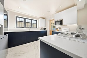 A modern kitchen with a marble countertop, a built-in oven, and a window with a view.