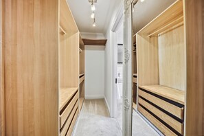 A walk-in closet with wooden shelving and a mirrored closet door.