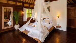 A bedroom with a canopy bed, a large mirror, a potted plant, and a nightstand with a lamp. - Ubud 1BR Villa Wooden Resort Sahadewa (Gianyar)