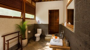 A bathroom with a wooden ceiling, a toilet, a sink with a basin, and a mirror. - Ubud 1BR Villa Wooden Resort Sahadewa (Gianyar)