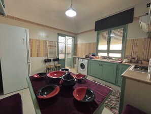 A compact kitchen with a washing machine, a sink, and a dining area with a table set for four. - THE MEDINA Rooftop
it’s a spacious villa in the peaceful heights of Montfleury (Tunis)