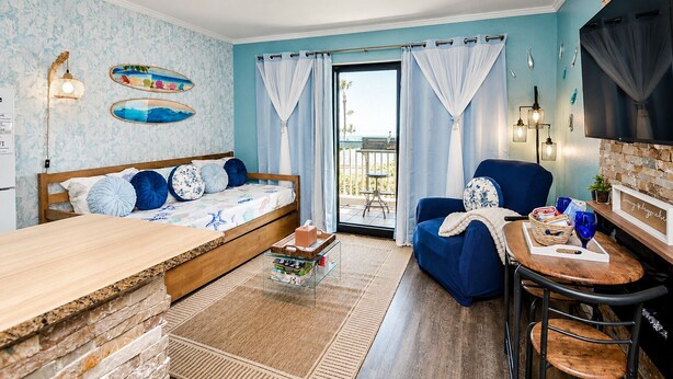 Ein Zimmer mit einem Bett, einem Sessel, einem Tisch und einem Fernseher.