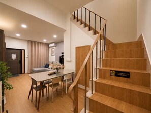 Een modern interieur met een houten trap, een eethoek met tafel en stoelen, en een bank.
