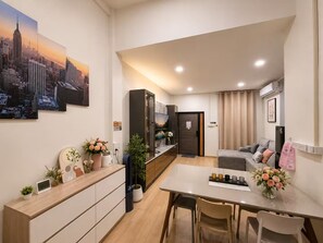 A modern living space with a dining area, a sofa, and a view of a cityscape. - Private Villa for 10 in Bangkok (Thanon Petchaburi, Ratchathewi)