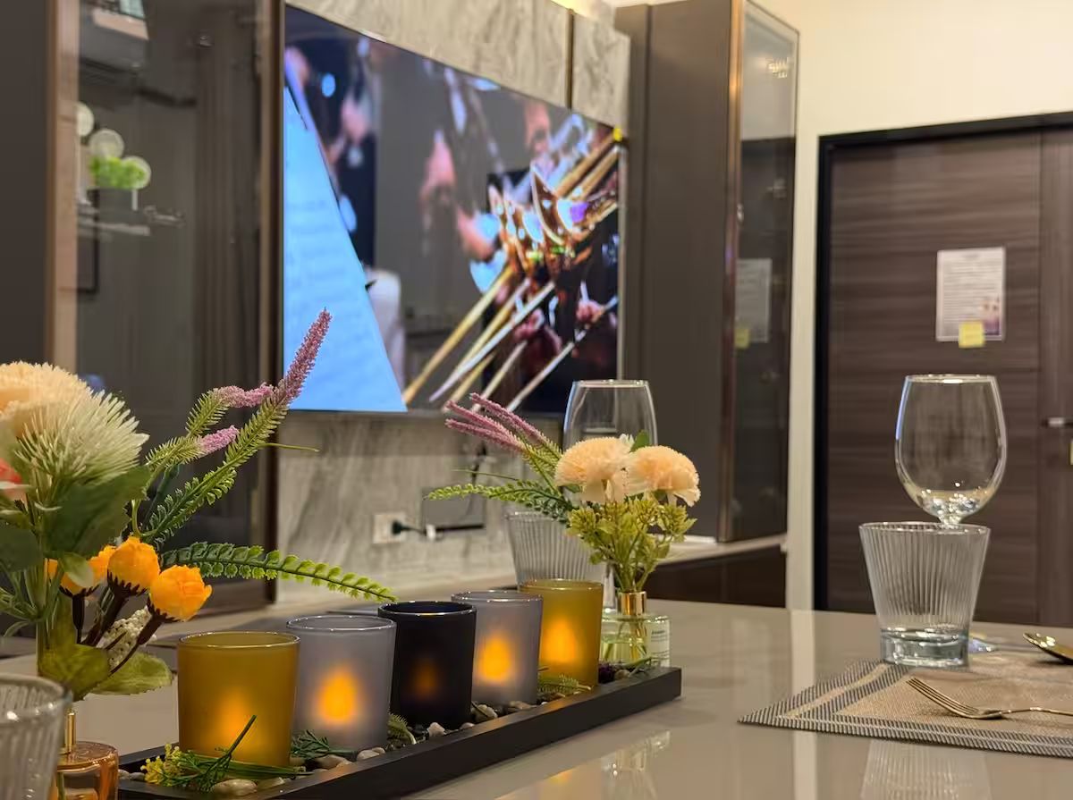 Ein Hotel-Rezeptionsbereich mit Flachbildfernseher, Kerzen, Blumen und einer Serviertablett mit Gläsern und Besteck.