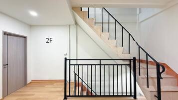 Eine Treppe mit schwarzem Metallgeländer, Holzboden und einer Wand mit einer Tür, auf der '2F' steht.