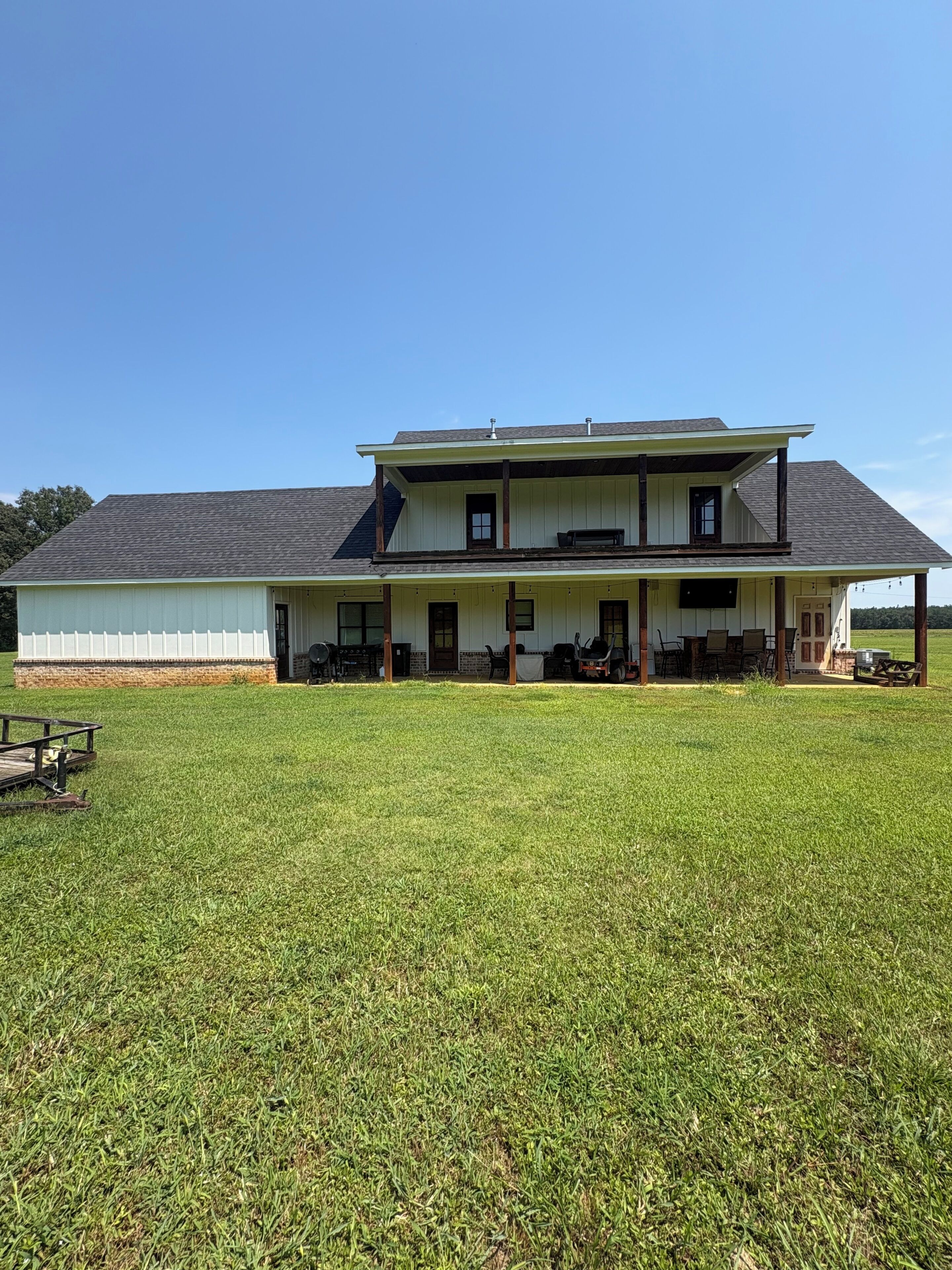 A two-story house with a porch and a large lawn in front.