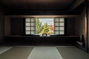 Une pièce de style japonais traditionnel, avec un sol recouvert de tatamis, une table basse et une fenêtre dotée de panneaux coulissants en papier de riz (shoji).
