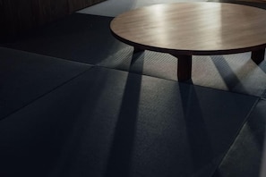 Une table ronde en bois, posée sur un plancher foncé.