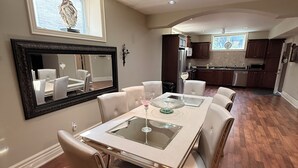 A dining area with a table and chairs, a kitchen in the background, and a ceiling with recessed lighting. - Home in Richmond Hill. Cozy, clean and friendly (Richmond Hill)