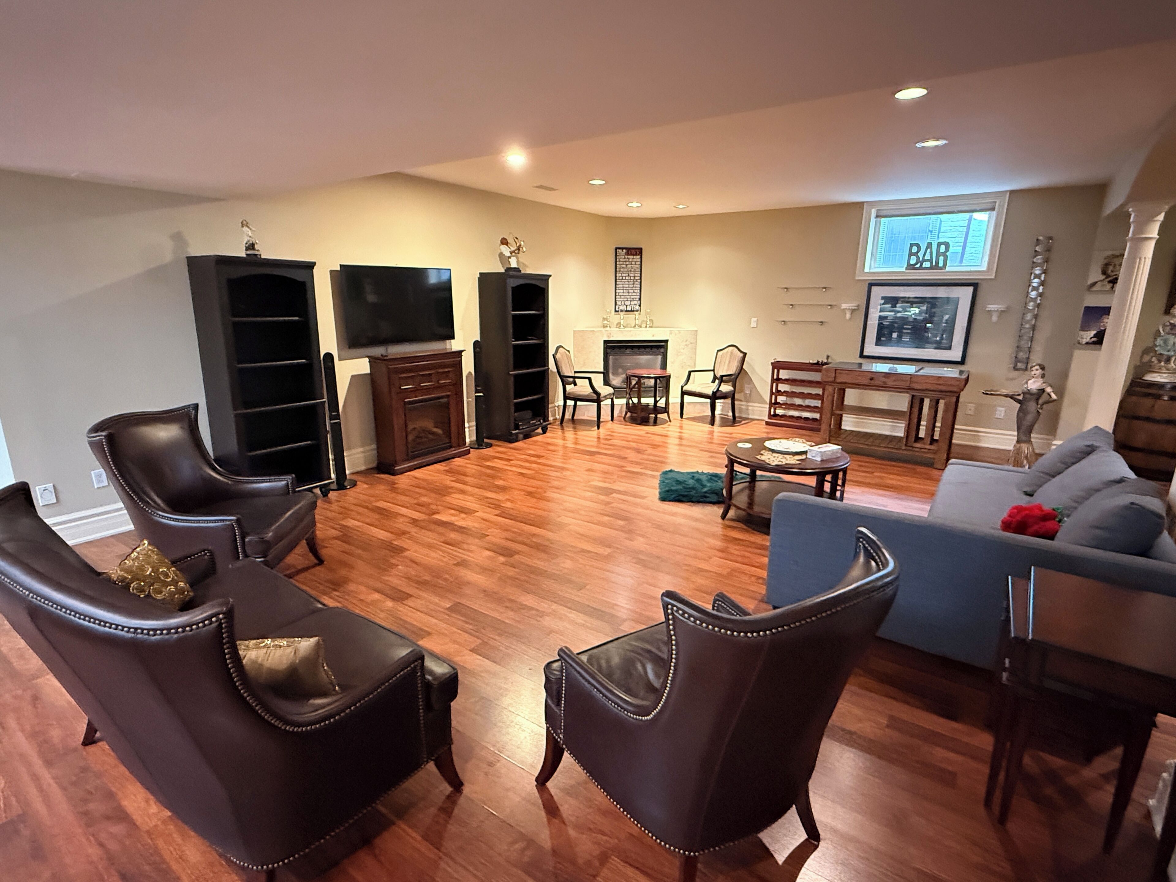 A living room with a fireplace, a flat-screen TV, leather chairs, a sofa, and a dining table.