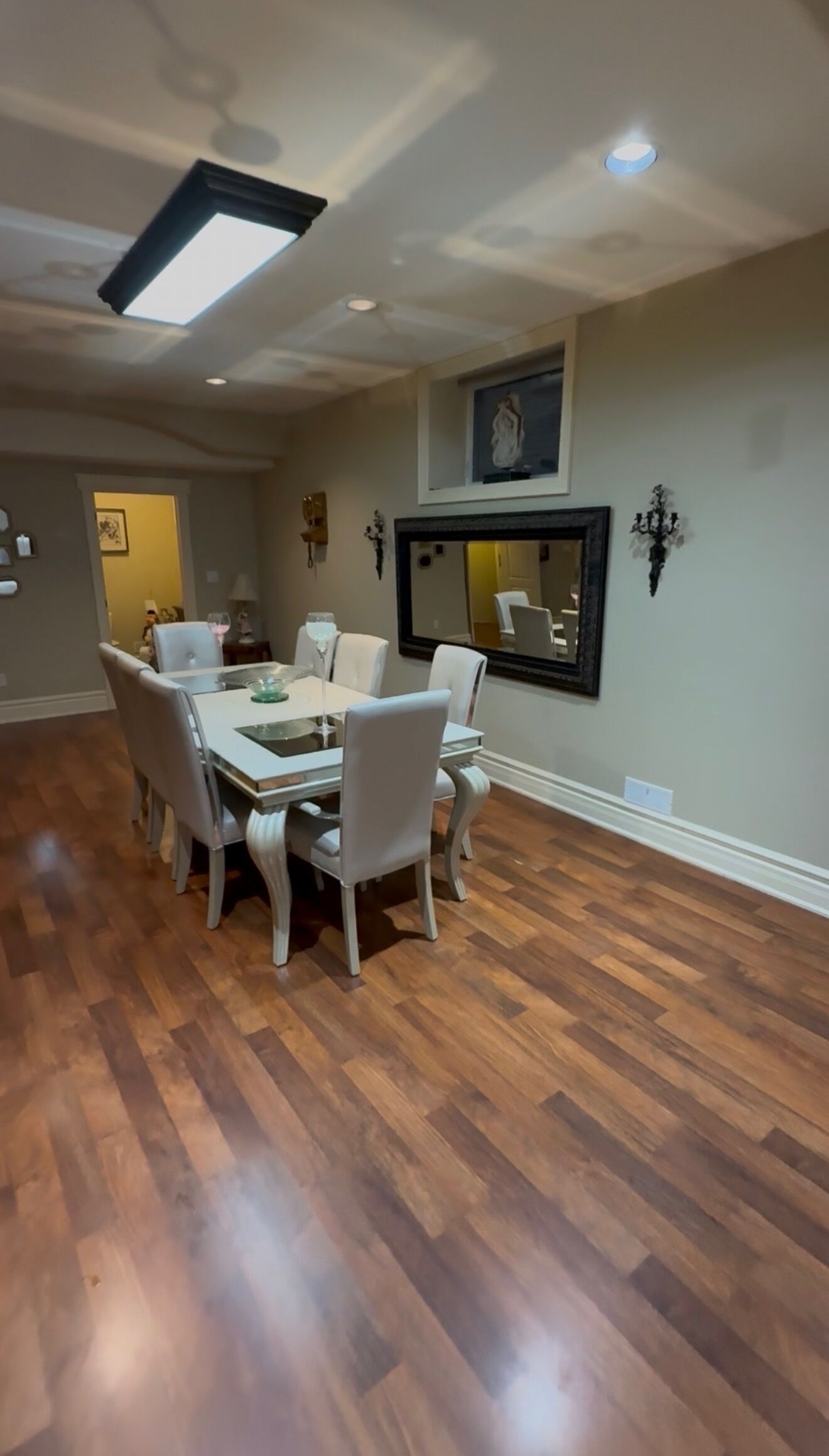 A dining area with a round table, six chairs, and a ceiling light fixture.