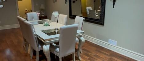 A dining area with a round table, six chairs, and a ceiling light fixture.