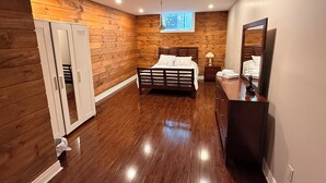A bedroom with a wooden floor, a bed, a dresser, a mirror, and a window. - Home in Richmond Hill. Cozy, clean and friendly (Richmond Hill)