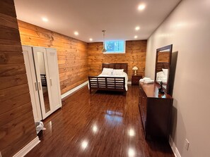 A bedroom with a wooden floor, a bed, a dresser, a mirror, and a window. - Home in Richmond Hill. Cozy, clean and friendly (Richmond Hill)