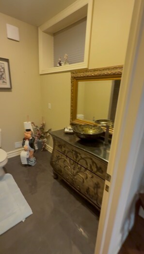 A bathroom with a large mirror, a vanity with a bowl sink, and a toilet. - Home in Richmond Hill. Cozy, clean and friendly (Richmond Hill)