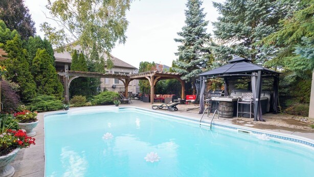 A swimming pool with a pergola and gazebo, surrounded by potted plants and trees. - Home in Richmond Hill. Cozy, clean and friendly (Richmond Hill)