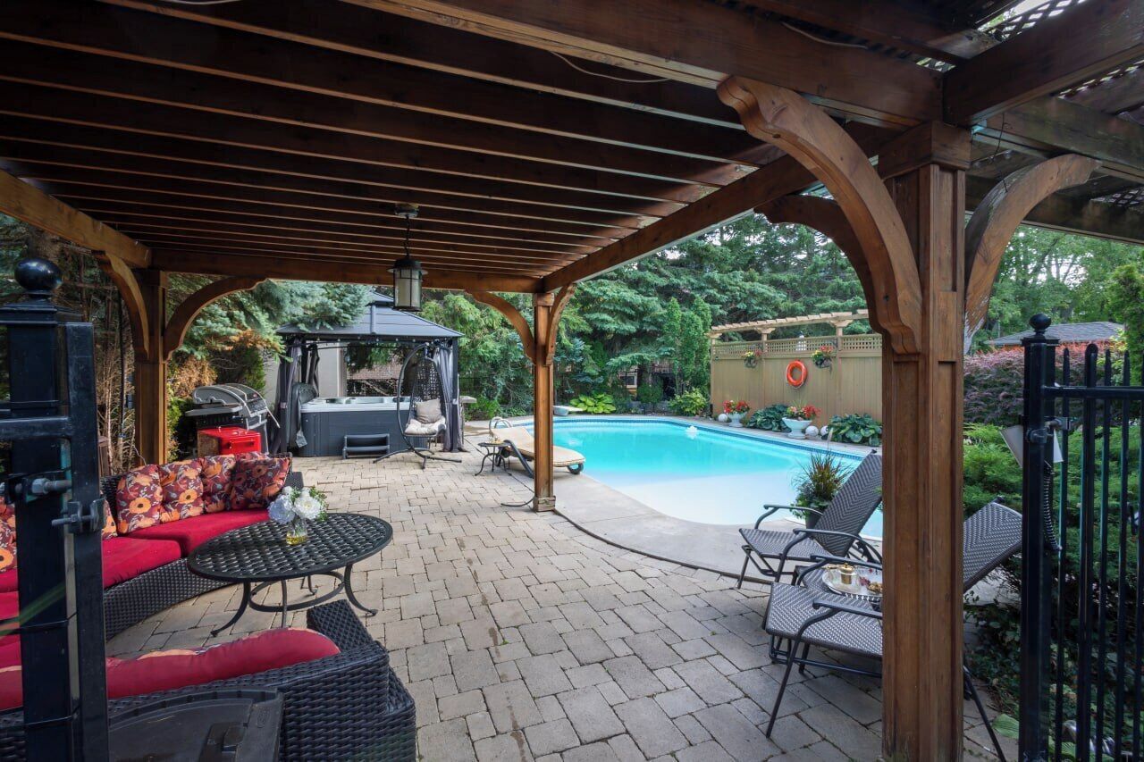 An outdoor patio with a pool, covered seating, and a barbecue area.