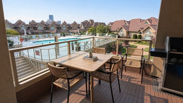 A balcony with a pool view, outdoor furniture, and a barbecue grill. - 3 bedroom downtown condo - sleeps 6 - lake & pools (Kelowna)