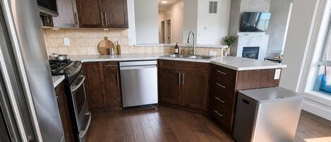 A modern kitchen with wooden cabinets, stainless steel appliances, and a dishwasher.
