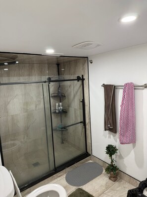 A modern bathroom with a glass-enclosed shower, a toilet, a sink, and a towel rack with a patterned towel. - 3-bedroom basement unit in Vaughan nice stay close to plazas outlets furnished (Vaughan)