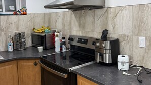 Et moderne køkken med komfur, ovn og emhætte i rustfrit stål. Der er en mikroovn, kaffemaskine og en Starfrit toaster på bordet.