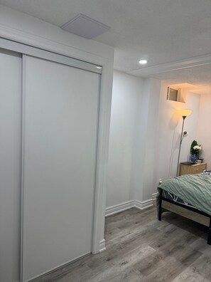 A bedroom with a closed closet, a bedside table with a lamp, and a bed with a green cover. - 3-bedroom basement unit in Vaughan nice stay close to plazas outlets furnished (Vaughan)