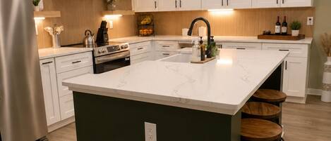 A modern kitchen with a central island, white cabinetry, and a stainless steel refrigerator.