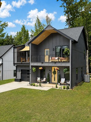 A modern two-story house with a balcony, a garage, and a well-maintained lawn.