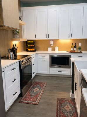 A modern kitchen with white cabinetry, a stainless steel range, and a microwave.