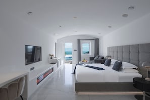 A modern hotel room with a large bed, a TV, a fireplace, and a view of the sea. - Dali MISTY HAVEN CAVE VILLA (Dali)