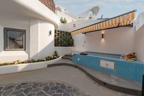 A modern outdoor pool area with a blue tiled wall, a stone floor, and a small bar area with a striped awning. - Dali MISTY HAVEN CAVE VILLA (Dali)