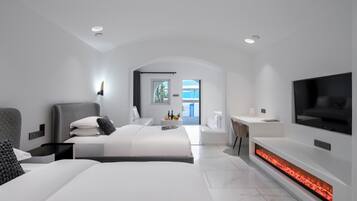 A modern hotel room with a large bed, a TV, a fireplace, and a view of the outdoors.
