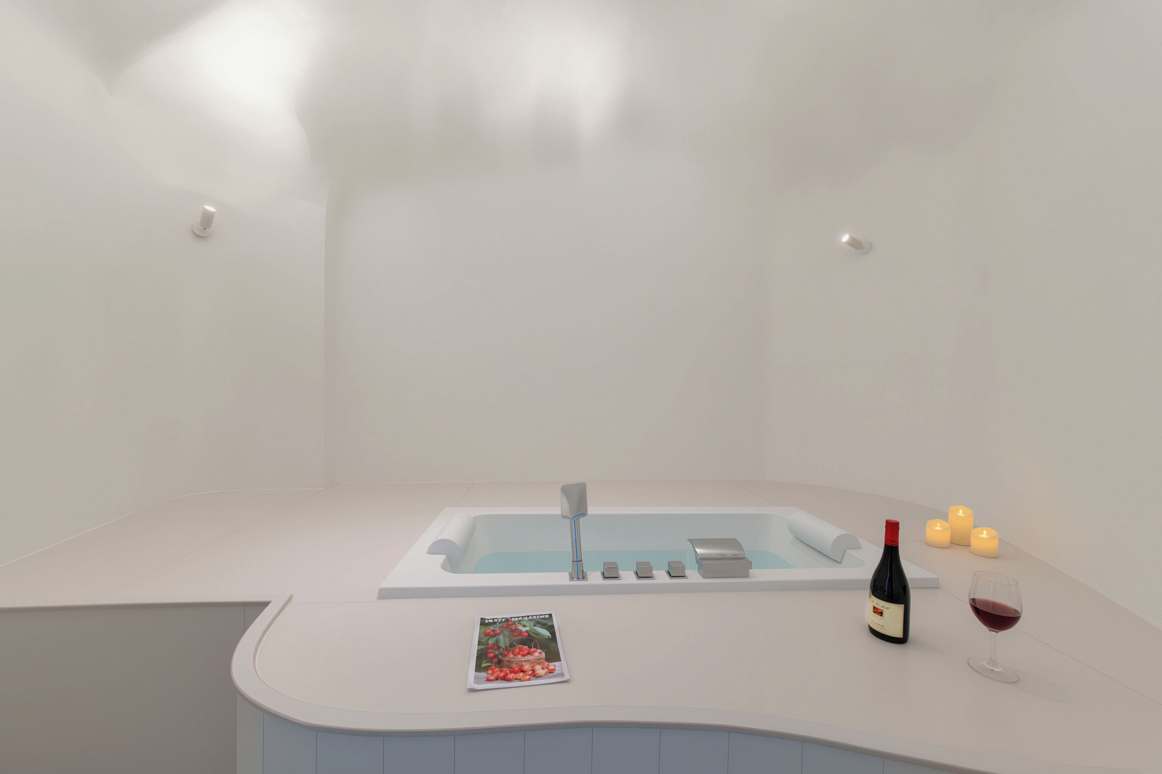 Un baño moderno con una bañera independiente, una revista en el mostrador, una botella de vino y velas.