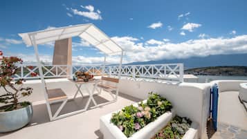 Una terraza con pérgola, mobiliario y vistas al mar.