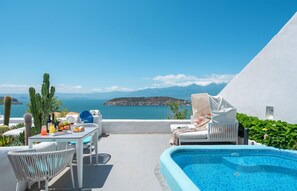 A poolside area with a table set for dining, a chair, and a view of the sea and mountains. - Dali MISTY HAVEN CAVE VILLA (Dali)