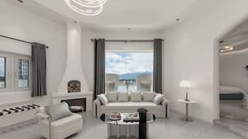A modern living room with a fireplace, a sofa, a coffee table, and a view of the sky and mountains.