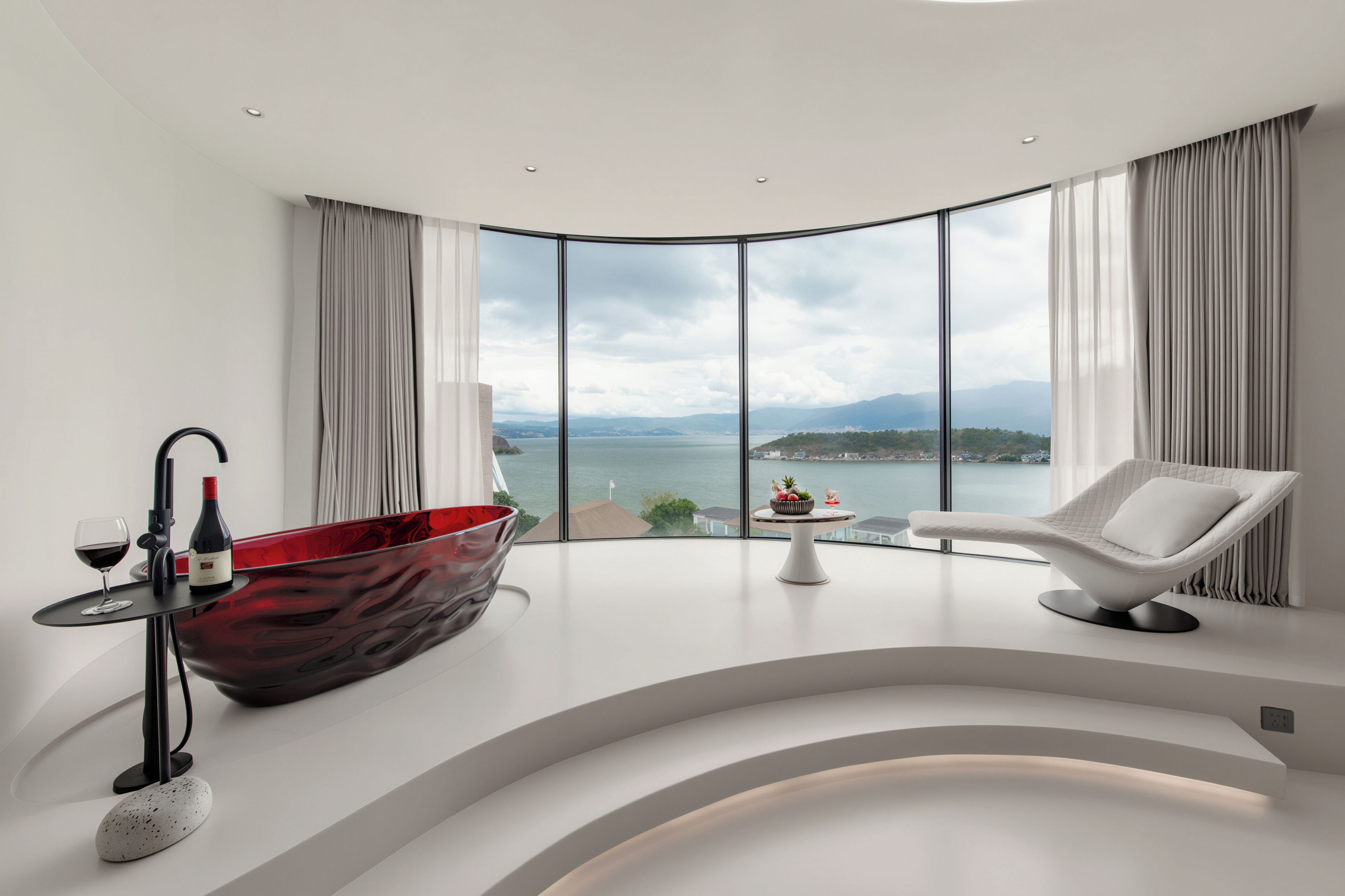 A modern bathroom with a large bathtub, a wine glass, and a bottle of wine on a side table.