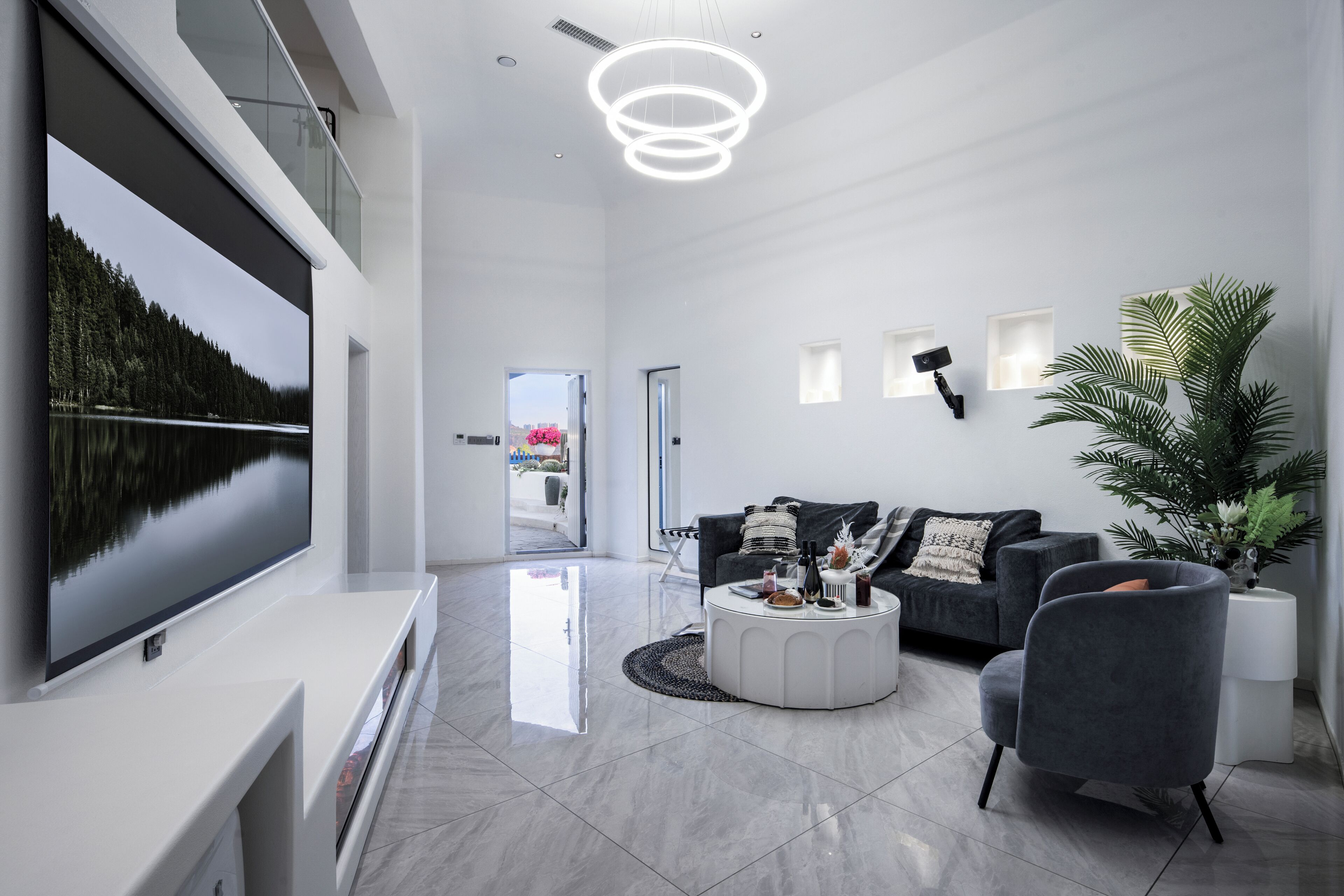 Una sala de estar moderna con un televisor de pantalla plana grande, un sofá gris, una mesa de centro y una planta en maceta.