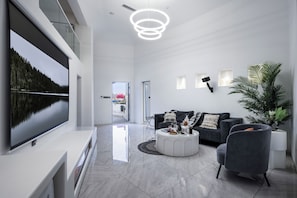 A modern living room with a large flat-screen TV, a grey sofa, a coffee table, and a potted plant. - Dali MISTY HAVEN CAVE VILLA (Dali)