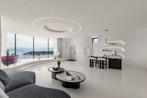 Una sala de estar moderna con un sofá curvo, una mesa de centro y un comedor con isla de cocina.