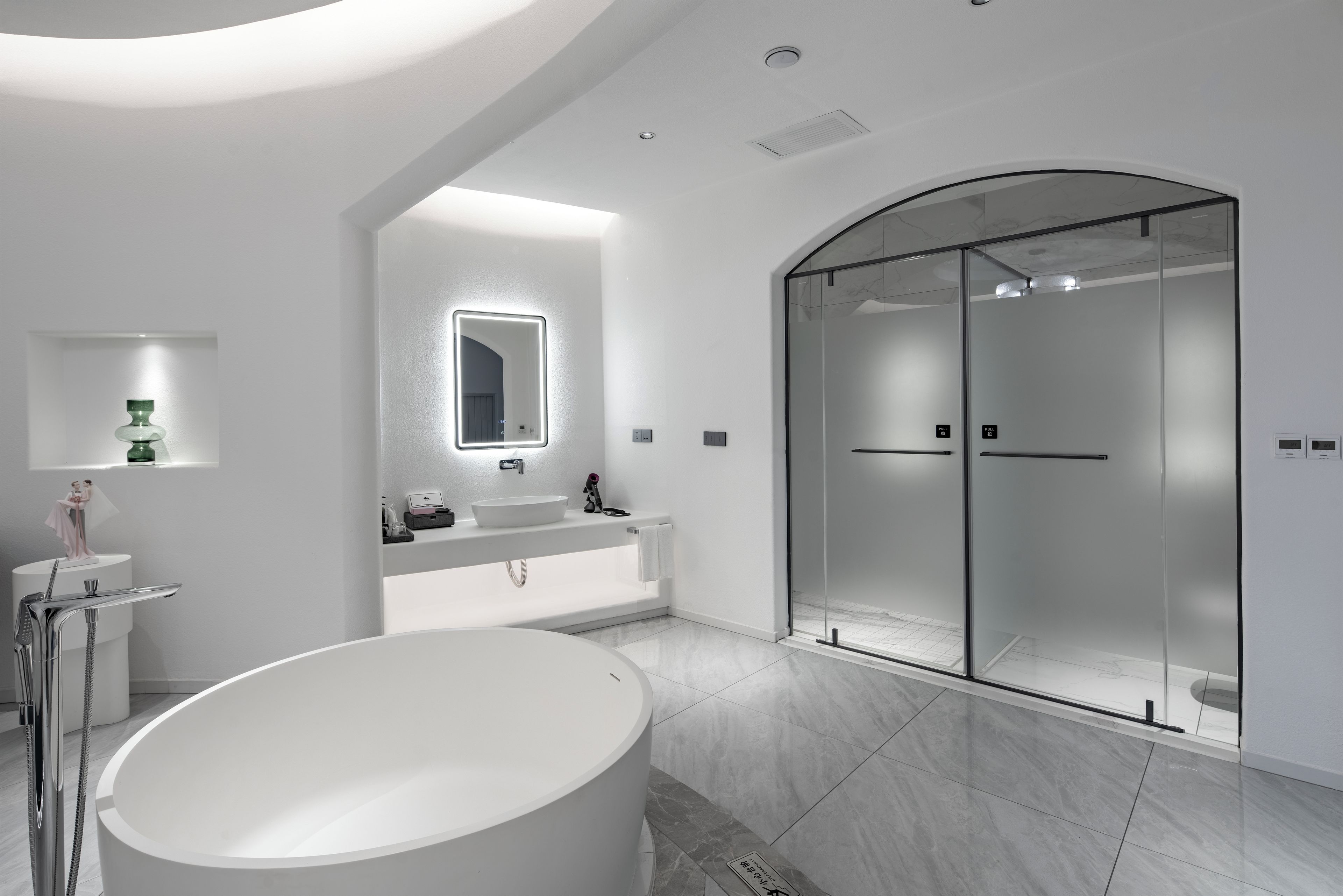 A modern bathroom with a freestanding bathtub, a glass-enclosed shower, and a vanity with a mirror.