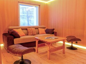 Una habitació acollidora amb un sofà, una taula de centre de fusta i una cadira.