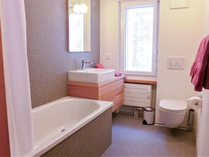 Un bany amb banyera, un lavabo, un vàter i una finestra.