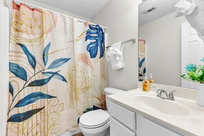Een badkamer met toilet, wastafel en douchegordijn.