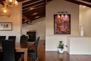 Una zona de menjador amb una taula i cadires de fusta, una làmpada penjant i una obra d'art emmarcada a la paret.