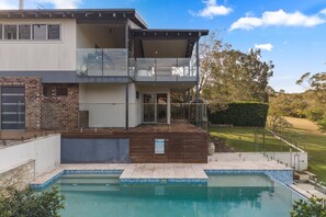 A two-story house with a swimming pool, a balcony, and a well-maintained garden. - Hallia House – Coastal Retreat (Readhead)