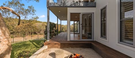 Una casa moderna con una terraza, una chimenea y vistas del paisaje circundante.
