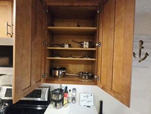A kitchen with wooden cabinets, stainless steel cookware, and a spice rack.