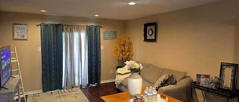 A living room with a wooden table, a sofa, a TV, and a decorative vase.